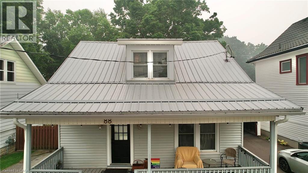 Siding exterior featuring a covered porch, white trim, and a prominent metal roof - 88 Brook Street, Simcoe, ON - Outdoor With Deck Patio Veranda With Exterior
