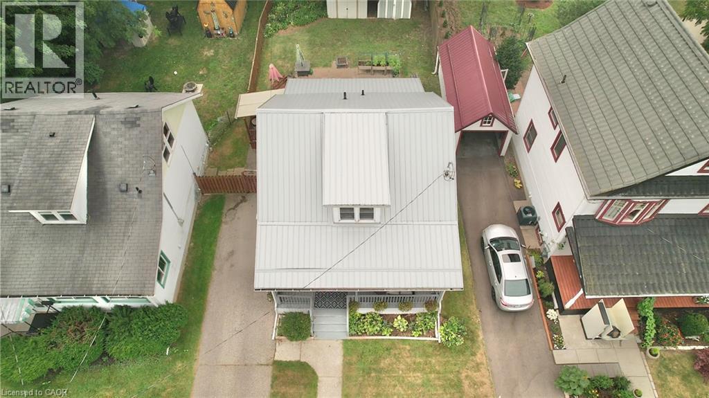 Property featuring a light gray metal roof, front porch with white railing, and a dormer window - 88 Brook Street, Simcoe, ON - Outdoor