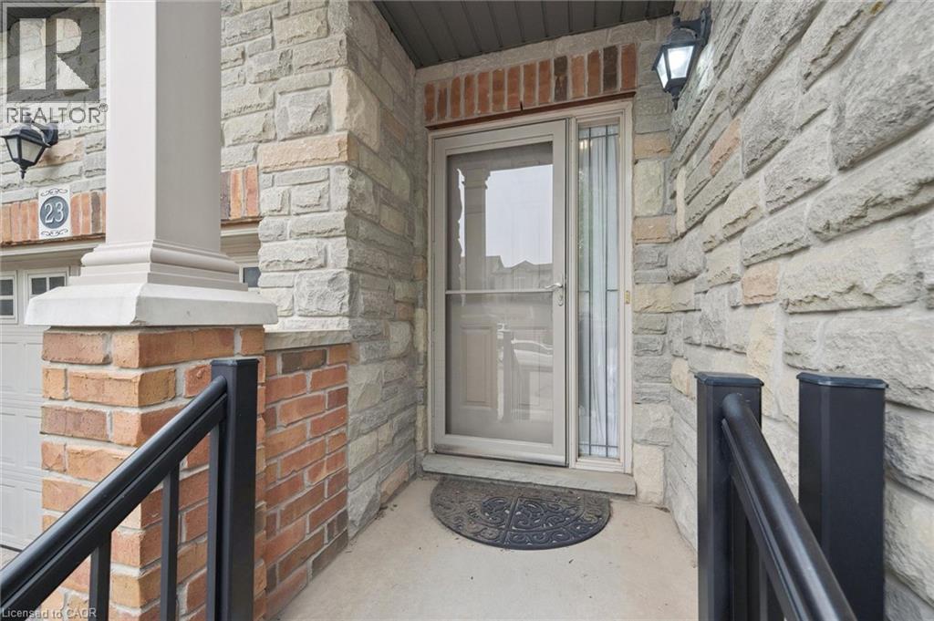 Stone and brick facade entryway featuring a storm door, an exterior light fixture, and a black metal handrail - 23 Knack Lane, Cambridge, ON - Photo Showing Other Room With Fireplace
