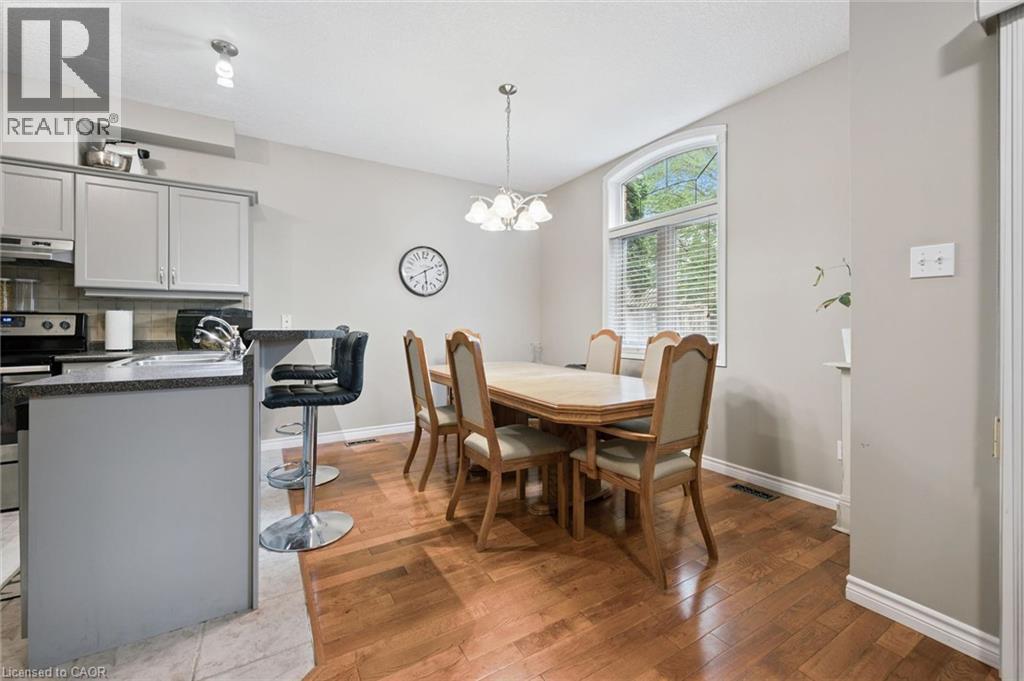 Open-concept kitchen and dining area featuring wood-finish flooring, a kitchen island with seating, pendant lighting, and a large window with an arched transom - 23 Knack Lane, Cambridge, ON - Indoor Photo Showing Dining Room