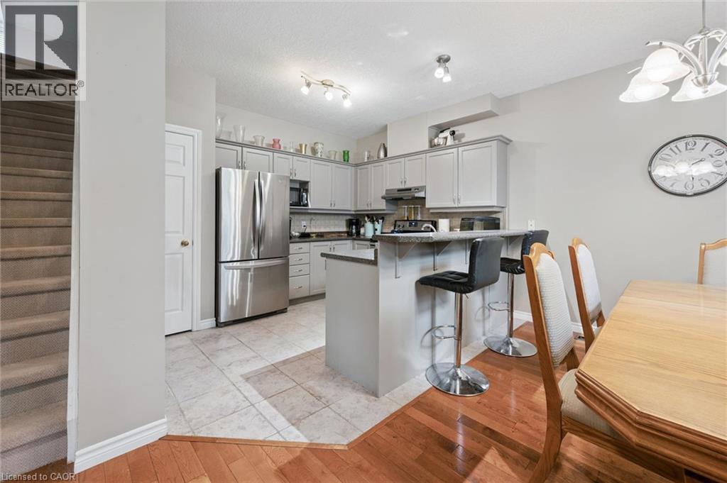 Kitchen featuring stainless steel appliances, light gray cabinetry, and a breakfast bar with seating - 23 Knack Lane, Cambridge, ON - Indoor Photo Showing Dining Room