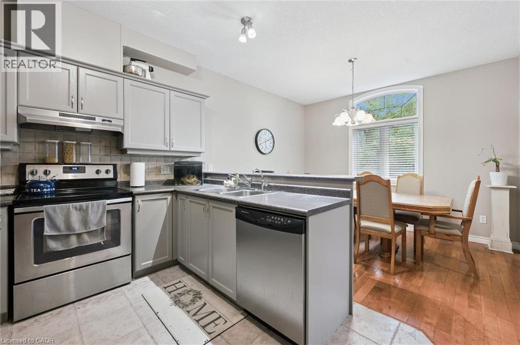 Modern kitchen featuring light gray cabinetry, stainless steel appliances, dark countertops, and tile flooring - 23 Knack Lane, Cambridge, ON - Indoor Photo Showing Kitchen With Double Sink