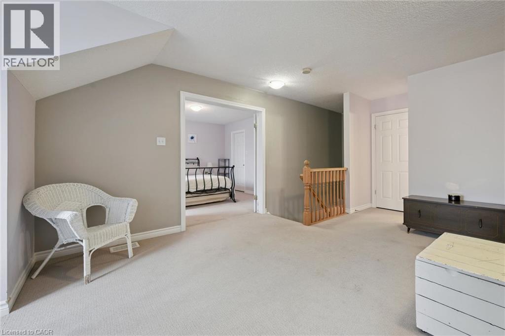 Carpeted flooring throughout, with a wood staircase railing and balusters - 23 Knack Lane, Cambridge, ON - Indoor Photo Showing Other Room