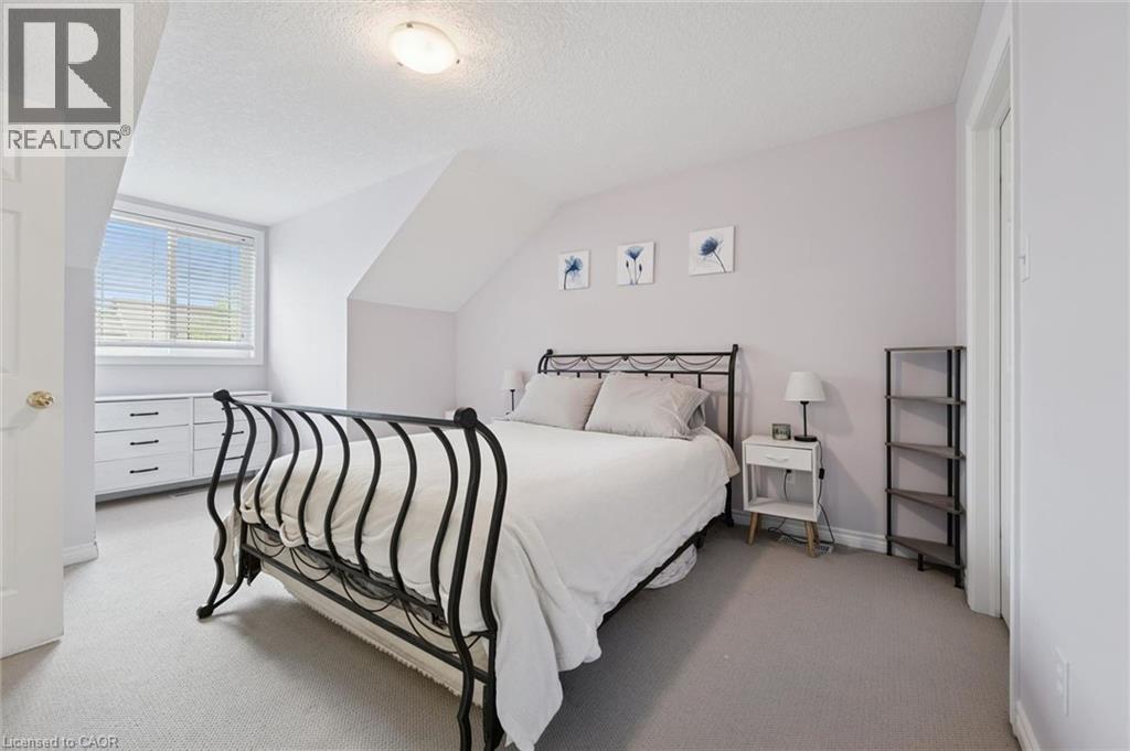 Carpeted bedroom featuring an angled ceiling, window with horizontal blinds, built-in dresser with dark hardware, and a semi-flush mount ceiling light fixture - 23 Knack Lane, Cambridge, ON - Indoor Photo Showing Bedroom