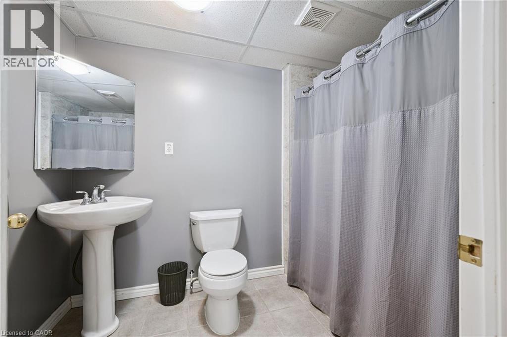 Full bathroom featuring a pedestal sink with a chrome faucet, a white toilet, and a shower area with a curtain rod - 23 Knack Lane, Cambridge, ON - Indoor Photo Showing Bathroom