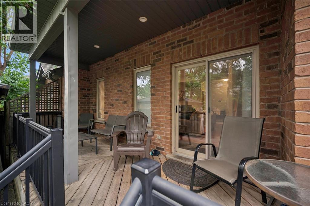 Covered outdoor deck with brick exterior, wood-finish flooring, and sliding glass door access - 23 Knack Lane, Cambridge, ON - Outdoor With Deck Patio Veranda With Exterior