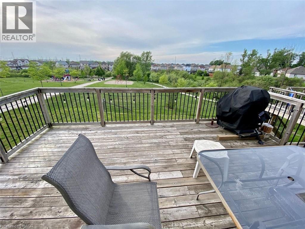 Spacious wood-finish deck with black metal spindle railing overlooking an expansive green space with mature trees - 287 Westmeadow Drive, Kitchener, ON - Outdoor With Deck Patio Veranda