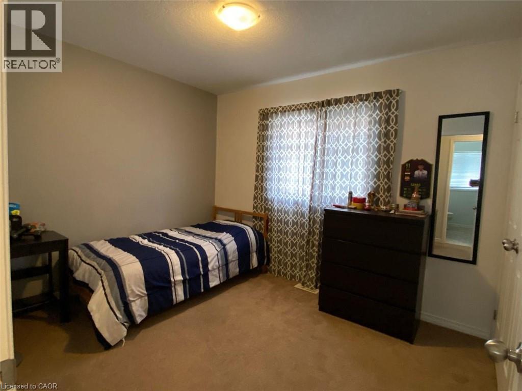 Carpeted room featuring neutral wall tones, a window with patterned drapes, and a flush-mount ceiling light - 287 Westmeadow Drive, Kitchener, ON - Indoor Photo Showing Bedroom
