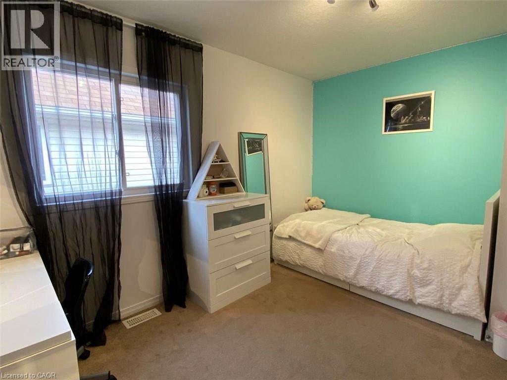 Inviting room featuring a large window with white trim, a distinct aqua accent wall, and recessed ceiling lighting - 287 Westmeadow Drive, Kitchener, ON - Indoor Photo Showing Bedroom