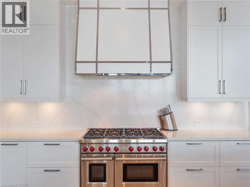 Professional-grade stainless steel range with red accents set against a white countertop and full-height backsplash - 140 Secord Lane, Burlington, ON - Indoor Photo Showing Kitchen With Upgraded Kitchen