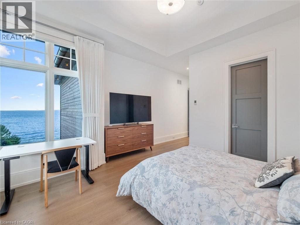Expansive window framing water, light wood-finish flooring, white walls, tray ceiling, and a paneled interior door - 140 Secord Lane, Burlington, ON - Indoor Photo Showing Bedroom