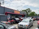 Commercial building with a grey brick facade and red trim, featuring a prominent red awning and a large sign - 350 Sherman Avenue N, Hamilton, ON 