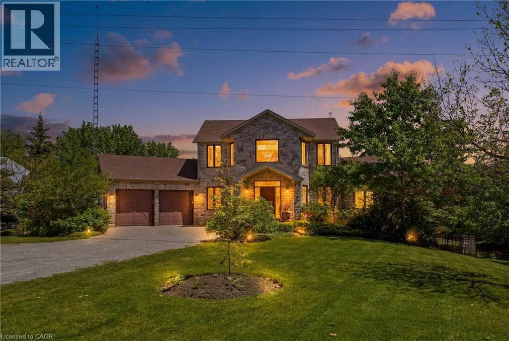 Stone facade residence featuring a two-car garage, mature landscaping, and an expansive front lawn - 5779 Third Line, Guelph/Eramosa, ON - Outdoor