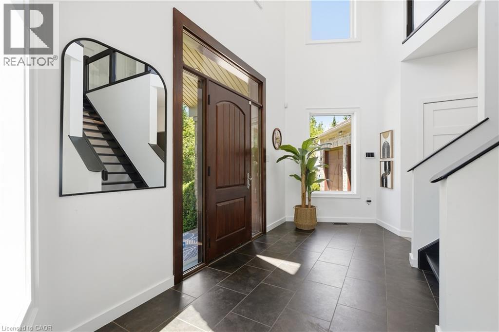Foyer featuring a dark wood-finish entry door with sidelights, dark tile flooring, a two-story ceiling, and a prominent staircase with dark handrails - 5779 Third Line, Guelph/Eramosa, ON - Indoor Photo Showing Other Room