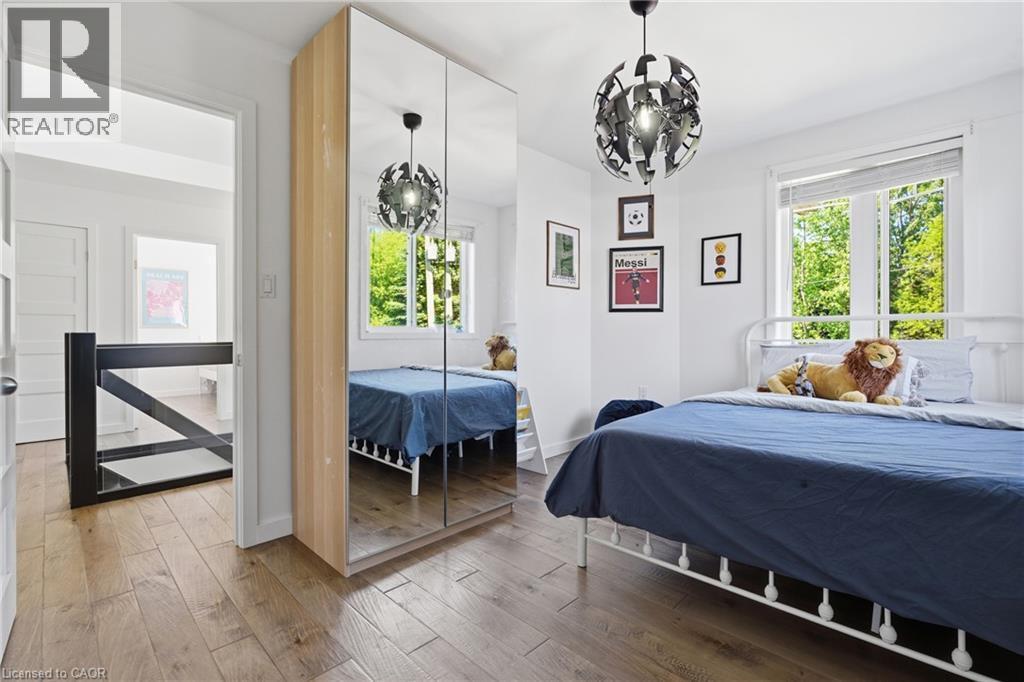 Bright interior space featuring wood-finish flooring, a contemporary ceiling light fixture, and a window with blinds - 5779 Third Line, Guelph/Eramosa, ON - Indoor Photo Showing Bedroom