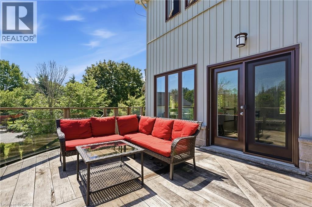 Expansive outdoor deck featuring weathered wood planks, a glass and wood railing, and direct access through a set of dark-framed glass doors - 5779 Third Line, Guelph/Eramosa, ON - Outdoor With Deck Patio Veranda With Exterior