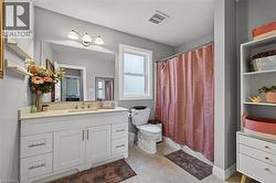 Bathroom featuring a single vanity with white cabinetry, light-toned countertop, and undermount sink -