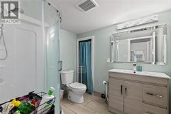 Bathroom featuring a glass-enclosed shower, a wood-finish vanity with an integrated sink, a large framed mirror, and a wall-mounted light fixture -