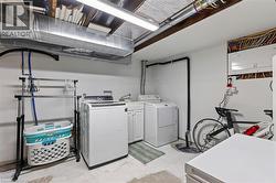 Dedicated laundry area featuring a white top-load washing machine, a white front-load dryer, and a utility sink with white cabinetry -