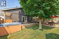 Expansive backyard featuring a manicured lawn, mature tree, and multi-level wood decking -