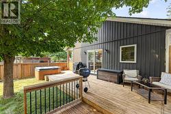 Wood deck with dark vertical siding, featuring a sliding glass door, a square window, a partial privacy fence, and a built-in outdoor spa -