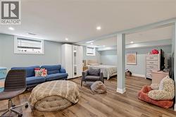 Spacious open-concept lower level with wood-finish flooring, recessed lighting, and light blue wall tones -