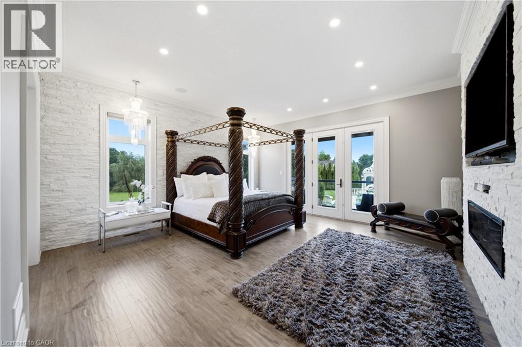Spacious interior featuring wood-finish flooring, white stacked stone accent wall, recessed lighting, and crown molding - 7009 Wellington Rd 34, Puslinch, ON - Indoor With Fireplace