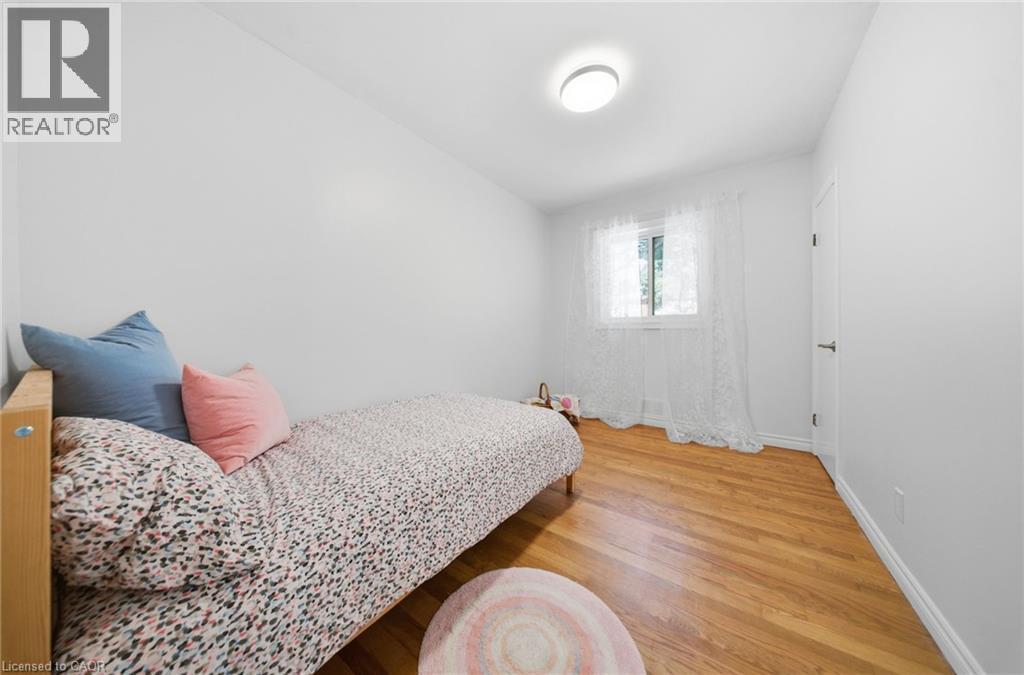 Bright room featuring wood-finish flooring, a window, and a ceiling-mounted light fixture - 80 Jackson Avenue, Kitchener, ON - Indoor Photo Showing Bedroom
