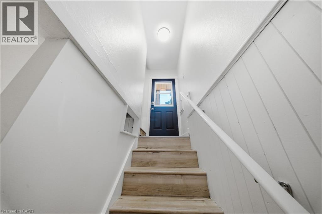 Staircase featuring wood-finish treads, a white handrail, and a dark entry door with window pane - 80 Jackson Avenue, Kitchener, ON - Indoor Photo Showing Other Room