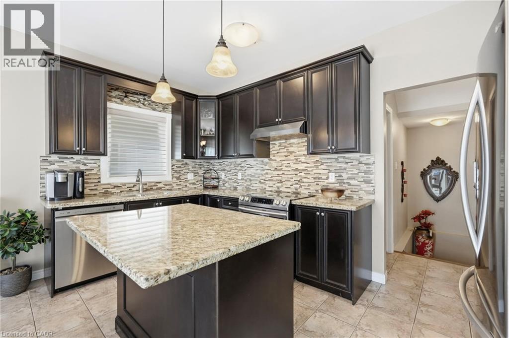Kitchen featuring dark cabinetry, a light granite island and countertops, stainless steel appliances, a mosaic tile backsplash, and tile flooring - 1332 Baseline Road, Stoney Creek, ON - Indoor Photo Showing Kitchen With Upgraded Kitchen