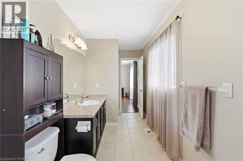Spacious bathroom featuring an elongated vanity with an integrated sink, a large wall mirror, and a multi-bulb light fixture - 1332 Baseline Road, Stoney Creek, ON - Indoor Photo Showing Bathroom