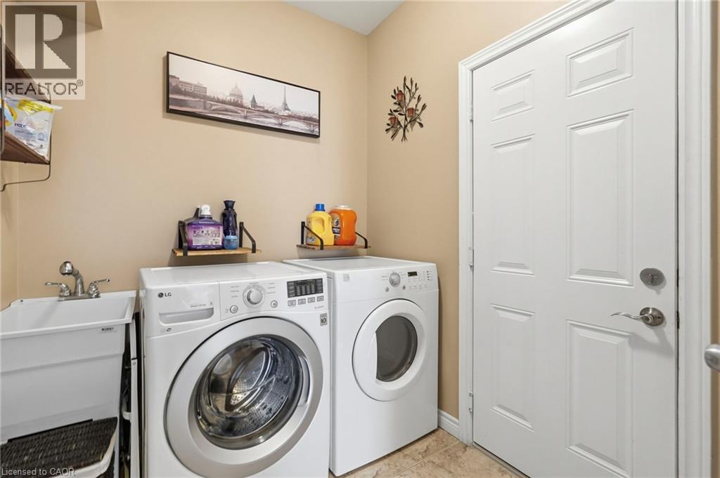 Dedicated laundry area featuring a utility sink with dual-handle faucet, full-size washer and dryer, and tiled flooring - 1332 Baseline Road, Stoney Creek, ON - Indoor Photo Showing Laundry Room