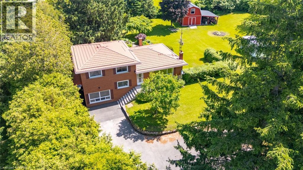 Brick two-story residence featuring a terracotta-hued tile roof, a paved driveway, and a red outbuilding in the rear yard - 1598 Highway No 6, Hamilton, ON - Outdoor