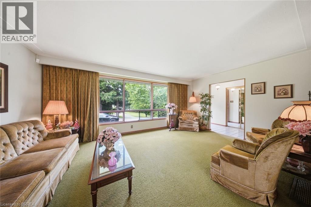 Spacious living area featuring expansive windows, green textile flooring, and white walls - 1598 Highway No 6, Hamilton, ON - Indoor Photo Showing Living Room
