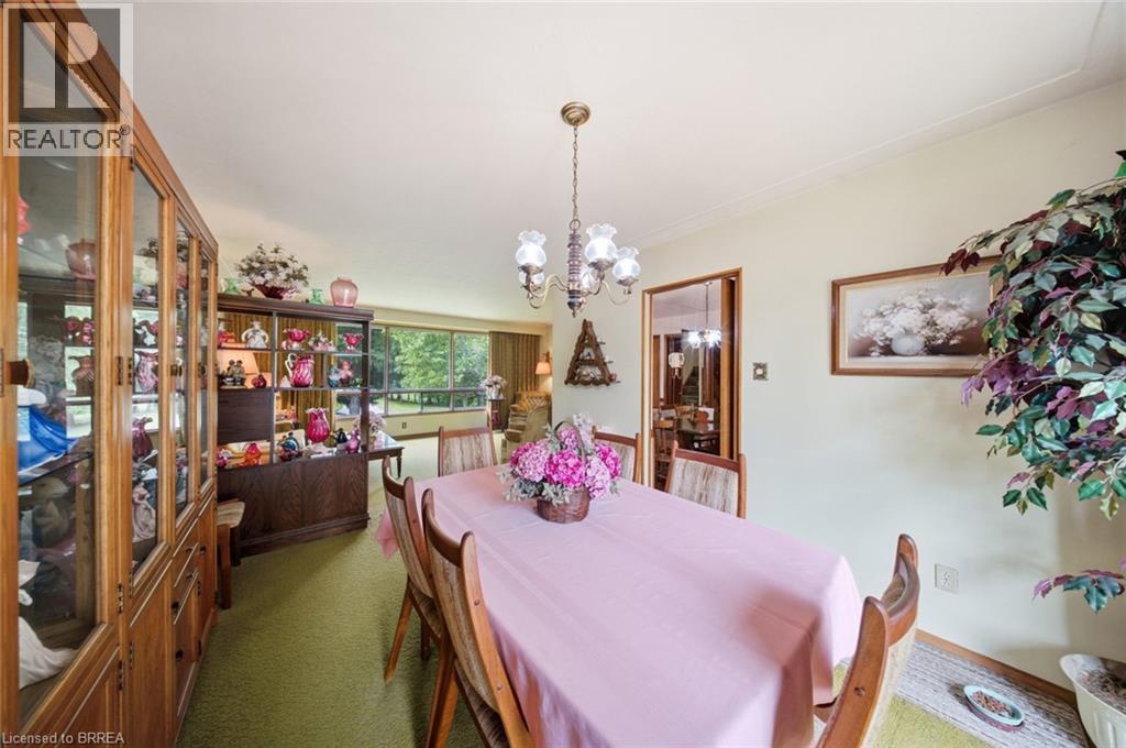 Dining area featuring a brass chandelier, wood-finish flooring, and light-toned walls - 1598 Highway No 6, Hamilton, ON - Indoor Photo Showing Dining Room