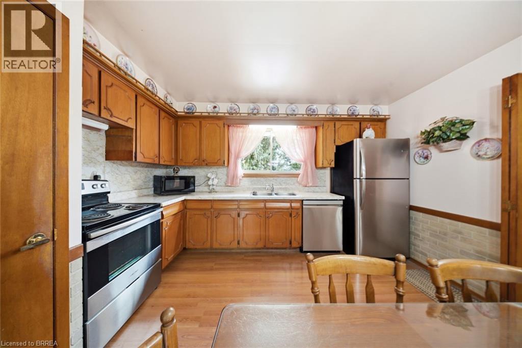 Functional kitchen featuring wood-finish cabinetry, white countertops, and wood-finish flooring - 1598 Highway No 6, Hamilton, ON - Indoor Photo Showing Kitchen With Double Sink