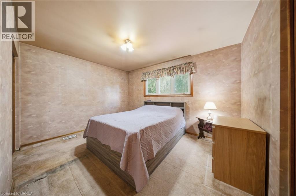 Bedroom featuring a window with exterior tree scenery, wood-frame window, and a flush-mount ceiling light fixture - 1598 Highway No 6, Hamilton, ON - Indoor Photo Showing Bedroom