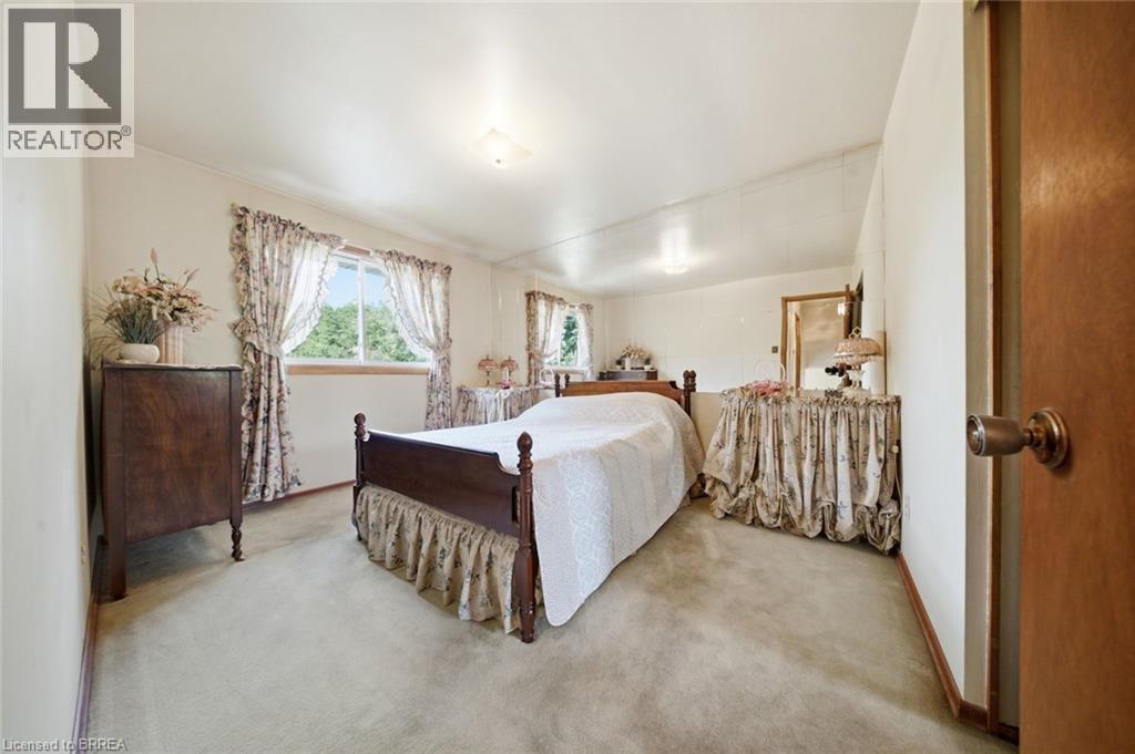 Carpeted interior space featuring a window with an exterior tree line, light-colored walls, and overhead lighting fixtures - 1598 Highway No 6, Hamilton, ON - Indoor Photo Showing Bedroom