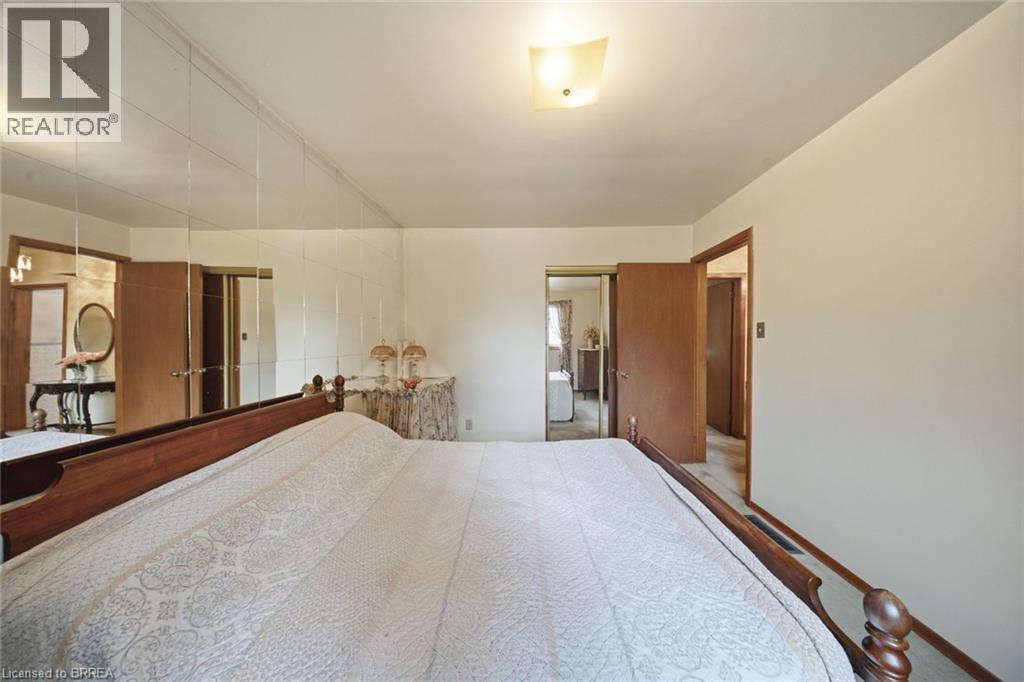 Spacious room featuring a mirrored accent wall, wood-finish interior doors, and a ceiling-mounted light fixture - 1598 Highway No 6, Hamilton, ON - Indoor Photo Showing Bedroom