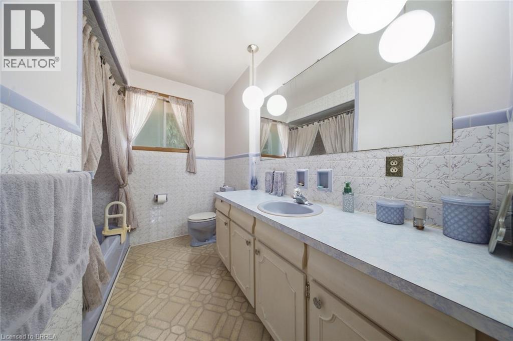 Bathroom vanity featuring a light-toned countertop, integrated sink, and wood-finish cabinetry - 1598 Highway No 6, Hamilton, ON - Indoor Photo Showing Bathroom