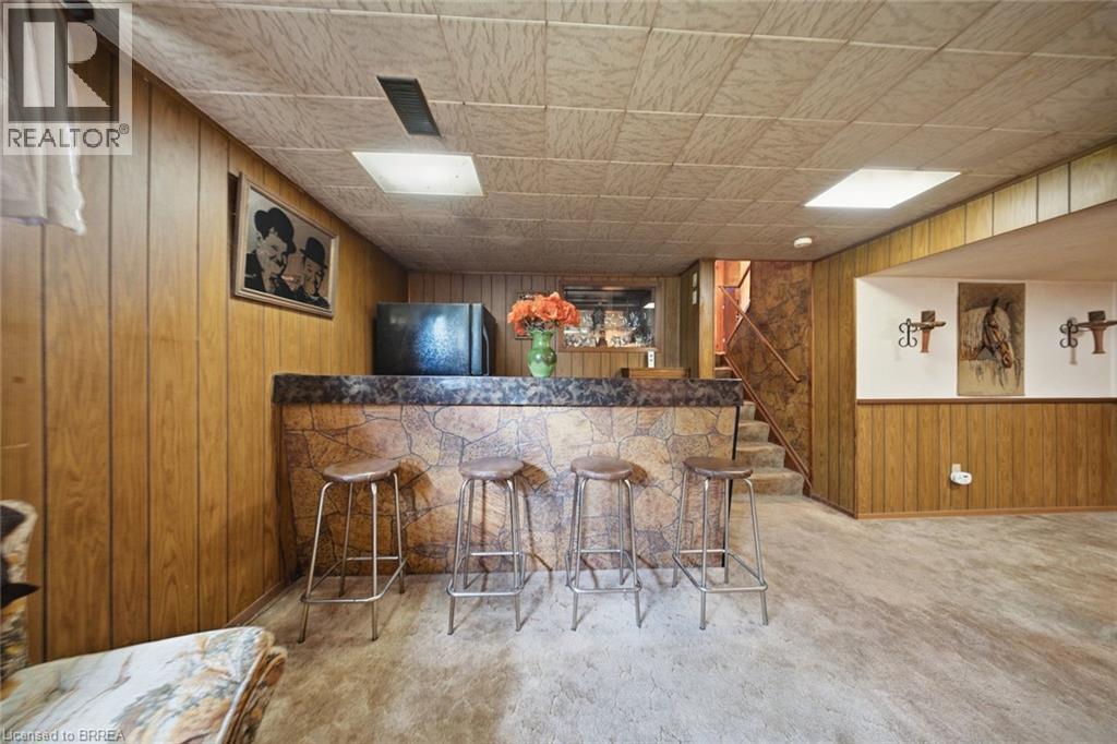 Recreation room featuring a built-in bar with a stone-finish facade, a textured countertop, and wood-panel walls - 1598 Highway No 6, Hamilton, ON - Indoor