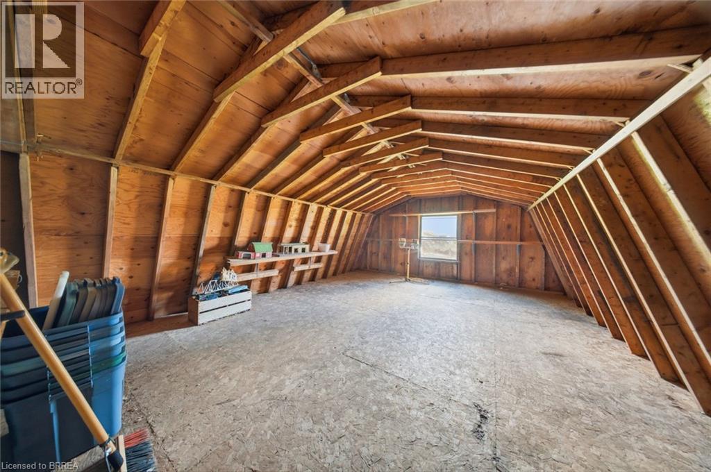 Spacious unfinished attic space featuring exposed wood framing, plywood walls, and a single window - 1598 Highway No 6, Hamilton, ON - Indoor Photo Showing Other Room