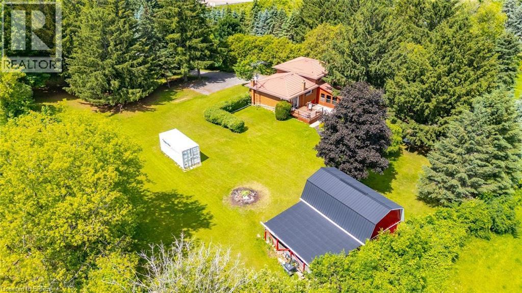 Expansive property featuring a red barn with a black roof, a residential structure with a reddish-brown roof, a large grassy area, and numerous mature trees - 1598 Highway No 6, Hamilton, ON - Outdoor