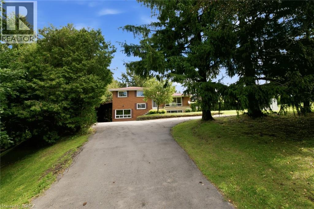 Brick exterior residence with multiple windows, a sloped asphalt driveway, and mature landscaping - 1598 Highway No 6, Hamilton, ON - Outdoor