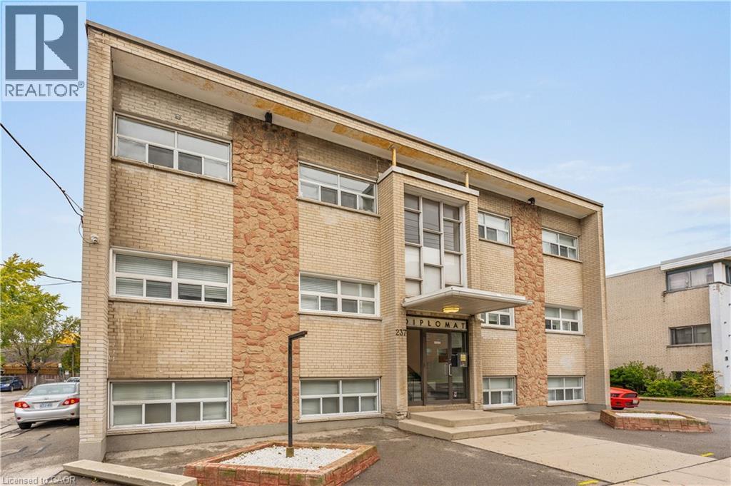Three-story building with a light brick facade and stone-clad accents - 237 Mohawk Road E Unit# 16, Hamilton, ON - Outdoor