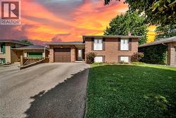 Brick exterior with a brown garage door, paved driveway, and a manicured front lawn - 