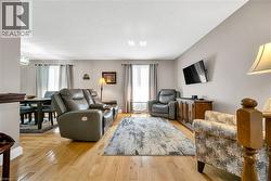 Open-concept living area with wood-finish flooring, neutral wall tones. - 