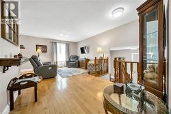 Living area featuring wood-finish flooring, light gray wall paint, and wooden display cabinet with glass panels - 
