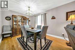 Dining area featuring wood-finish flooring, a decorative chandelier, and neutral wall tones - 