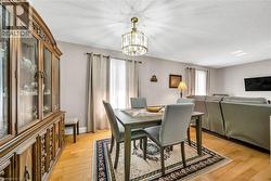 Dining area featuring wood-finish flooring, a decorative chandelier, and neutral wall tones - 